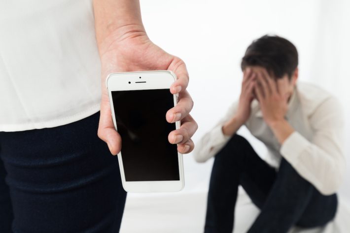 スマートフォンを持つ女性に頭を抱える男性