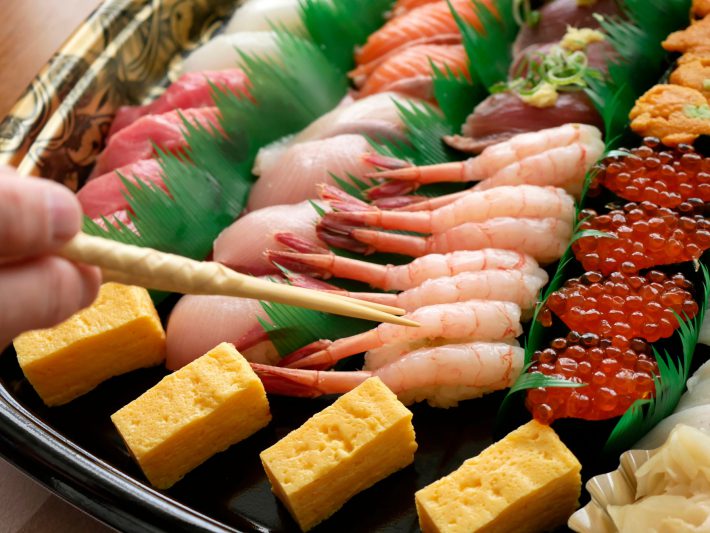 寿司桶に箸を伸ばす