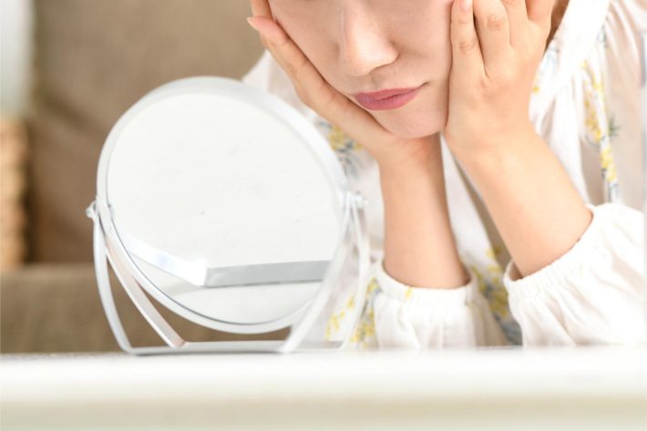 鏡をのぞきこむ女性