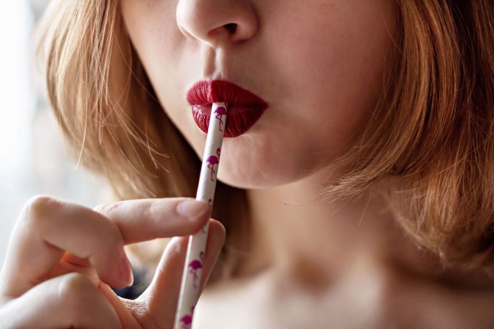 紙ストローでドリンクを飲む女性