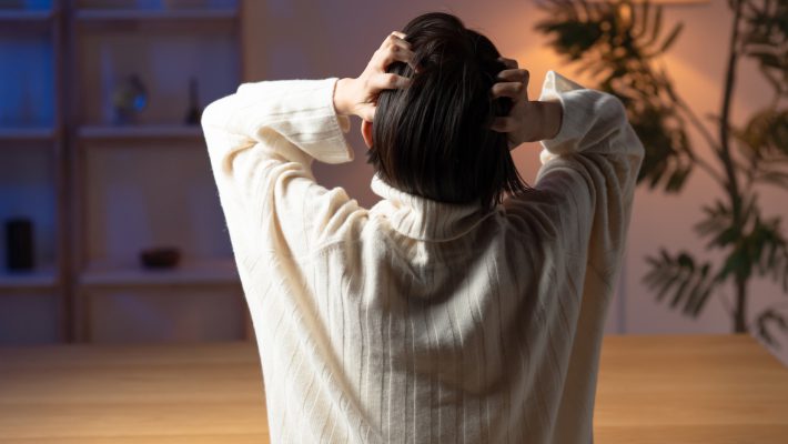 頭を抱える女性の後ろ姿