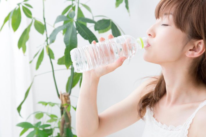 ペットボトルの水を飲む女性