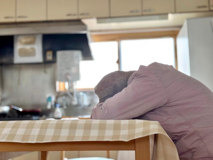 机に突っ伏す高齢女性