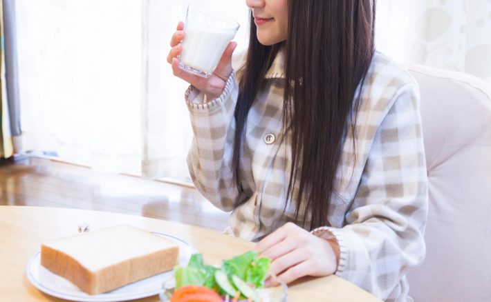 牛乳と一緒にパンを食べる女性