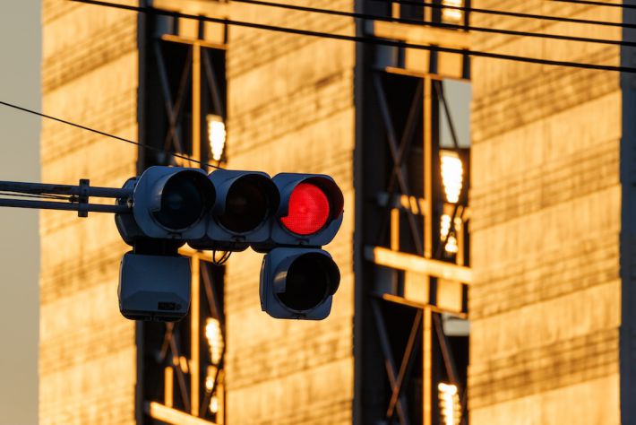 交差点の赤信号と朝日に黄色く光るビル