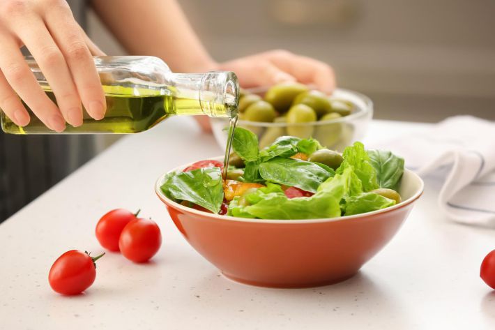 サラダにオリーブオイルをかける手