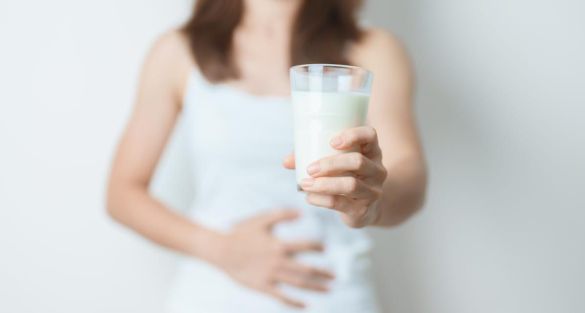 お腹に手をあてながらグラスを掲げる女性