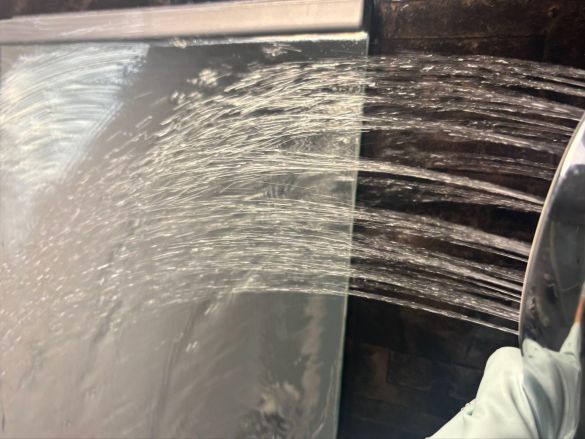 水で鏡についたクリームを流す様子